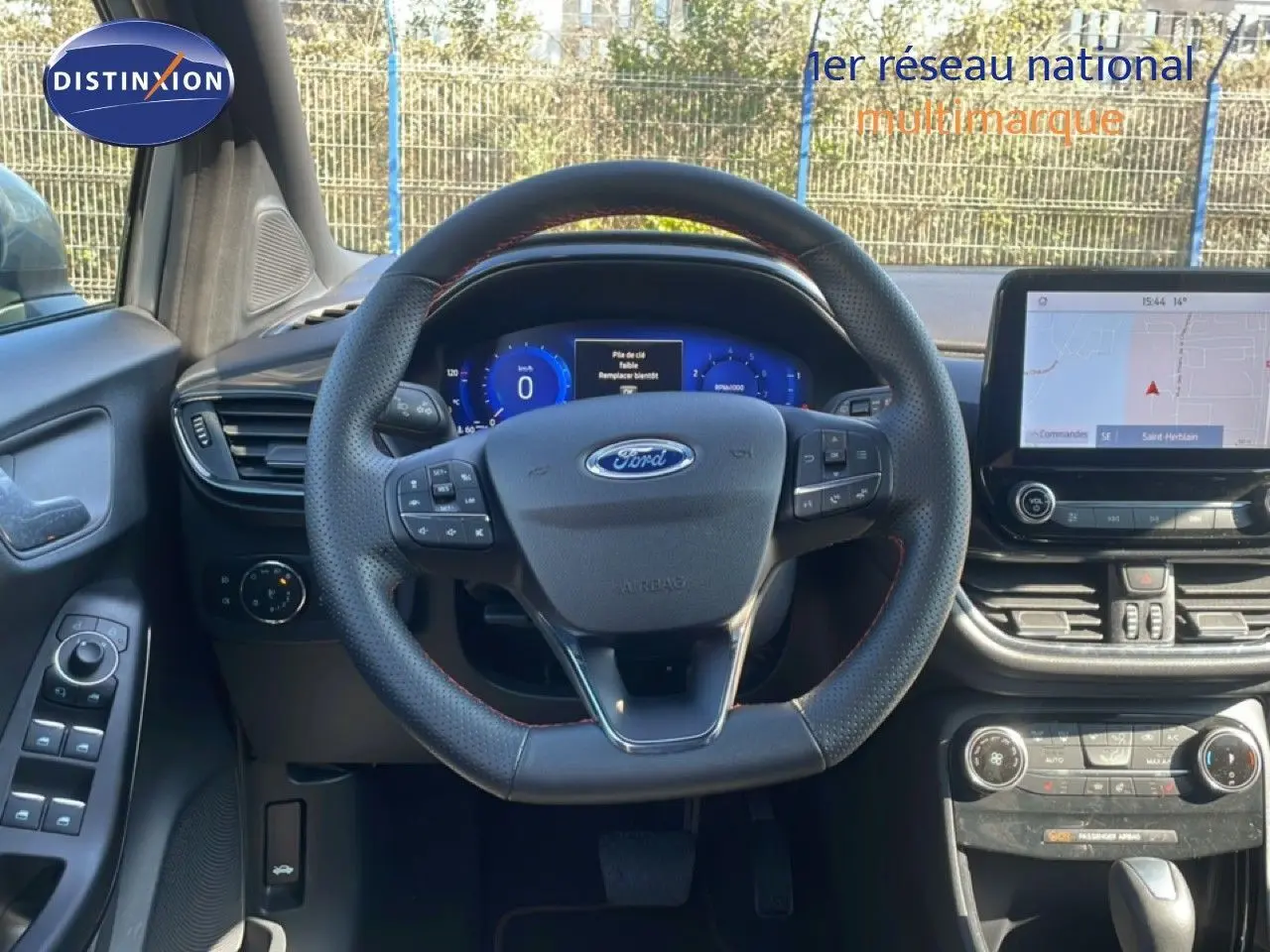 Vue intérieure frontale du tableau de bord et volant noir perforé de la Ford Puma gris Solar Metal 2023 avec écran tactile et commandes intégrées.