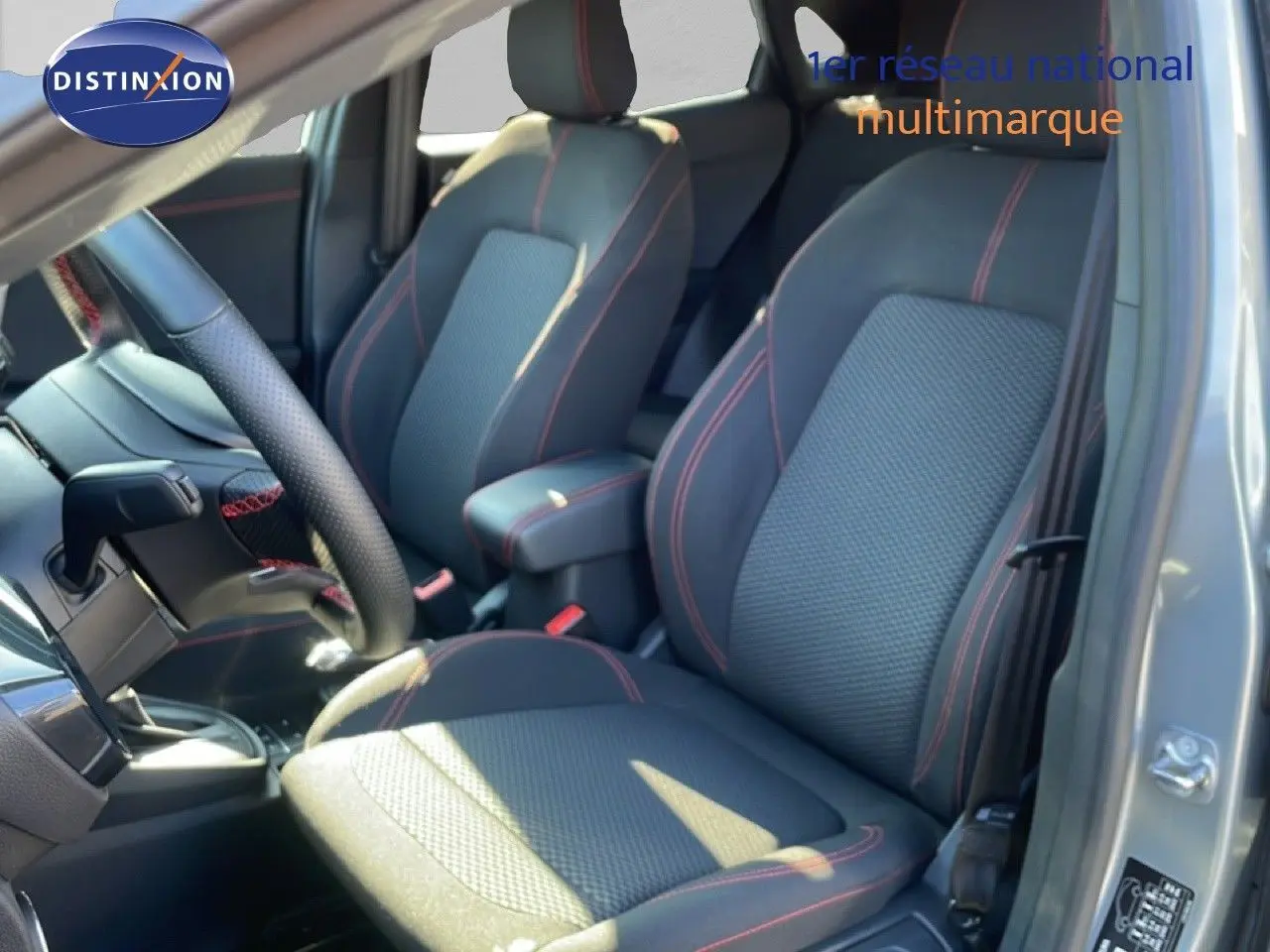 Vue intérieure côté conducteur du Ford Puma gris Solar Metal, sièges tissu noir avec surpiqûres rouges et volant cuir.