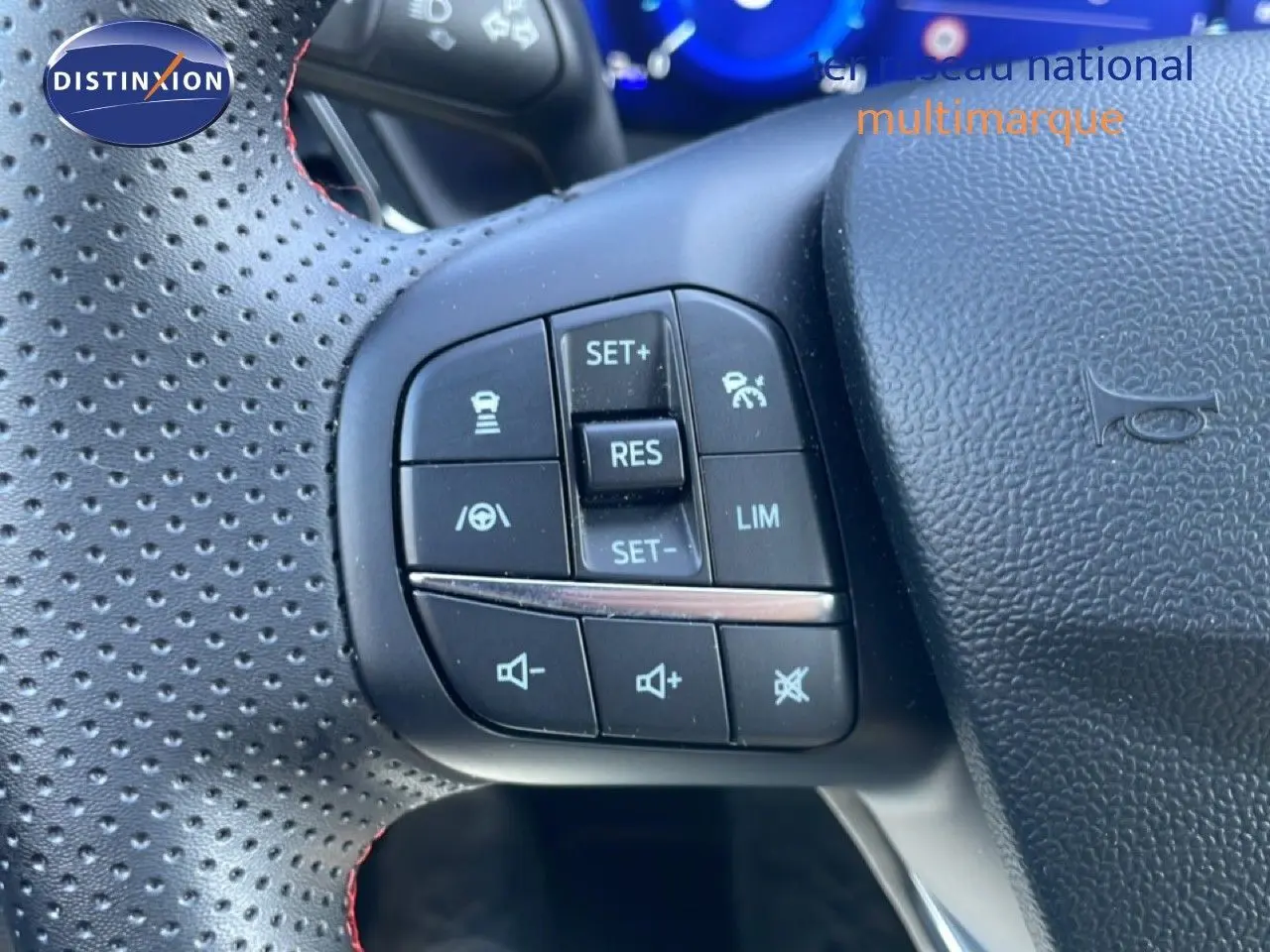 Gros plan sur les commandes de régulateur de vitesse au volant perforé noir du Ford Puma gris Solar Metal 2023.