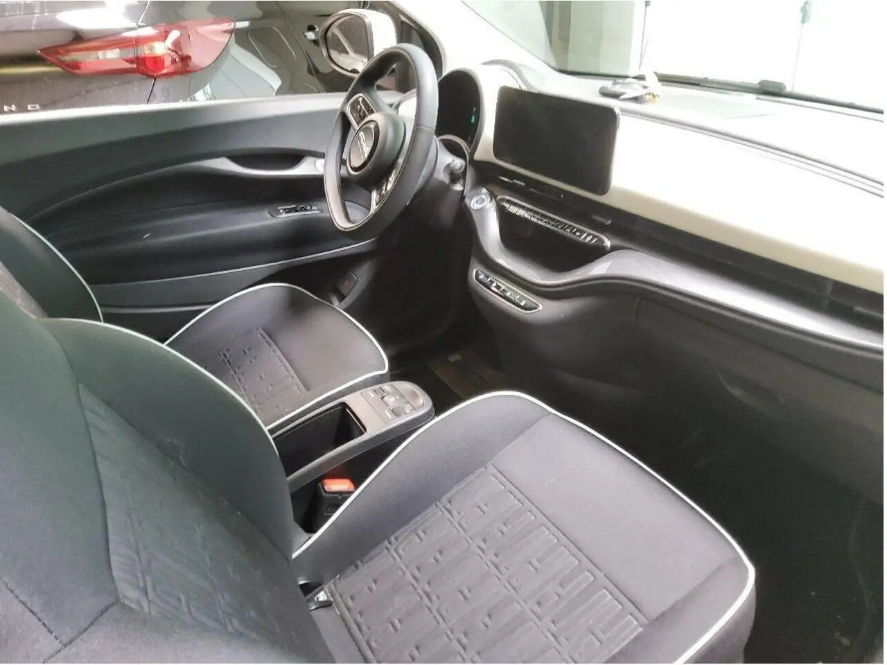 Vue 3/4 avant droite d'une Fiat 500 électrique blanche avec logo distinctif et jantes alliage multibranches.