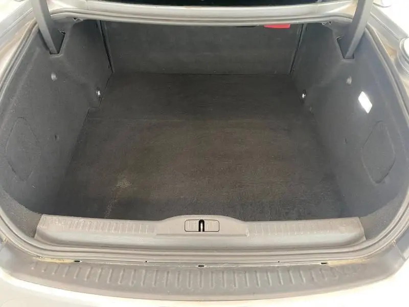 Coffre ouvert vu de face d'une Peugeot RCZ gris, montrant un espace de rangement propre et vide.