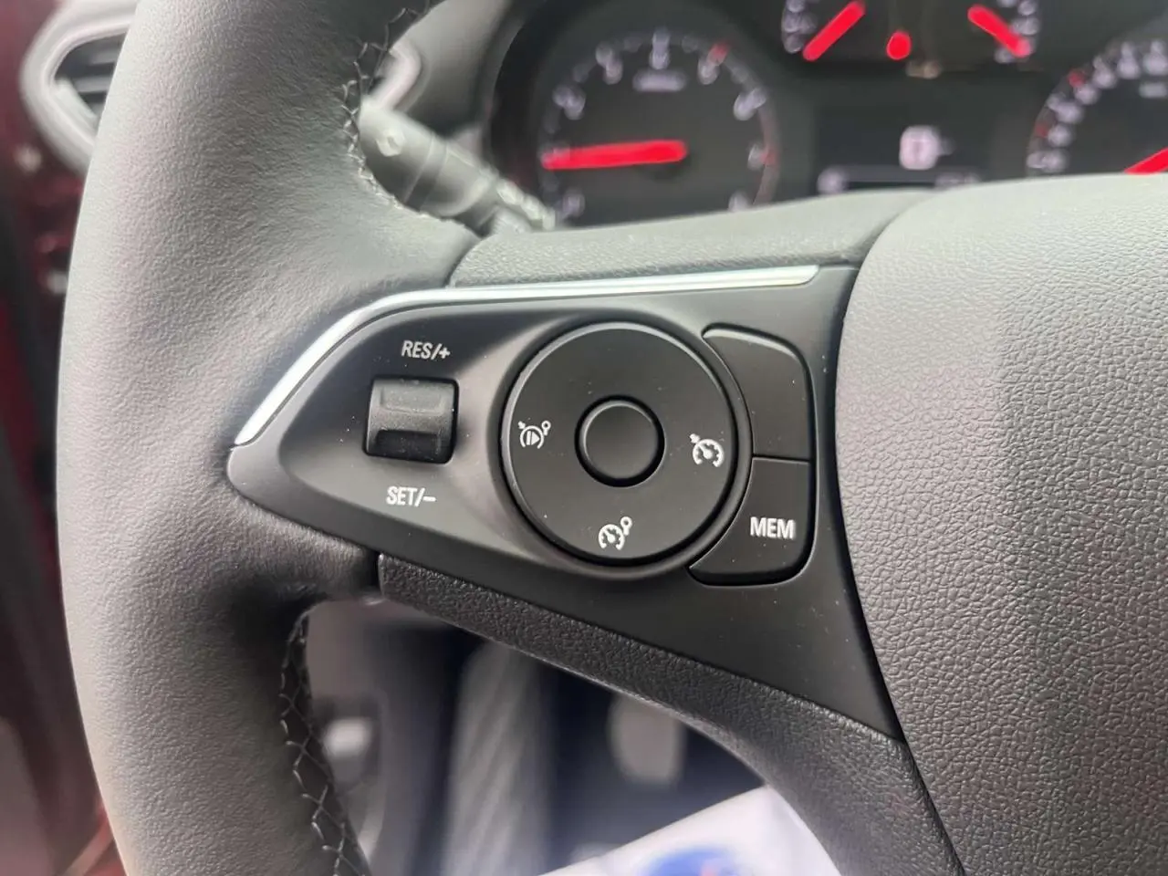 Gros plan sur les commandes au volant à gauche de l'Opel Crossland rouge 2022, avec boutons de régulateur de vitesse.