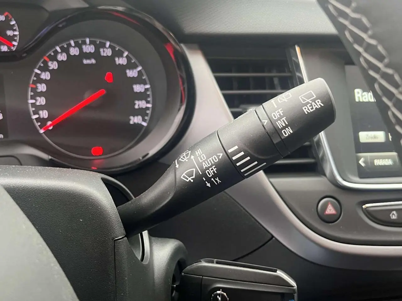 Gros plan sur la commande d’essuie-glace à droite du volant dans l’habitacle de l’Opel Crossland rouge 2022.