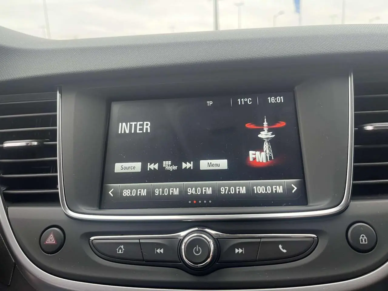 Écran tactile multimédia de l’Opel Crossland rouge 2022 affichant les stations FM avec commandes intégrées au tableau de bord.