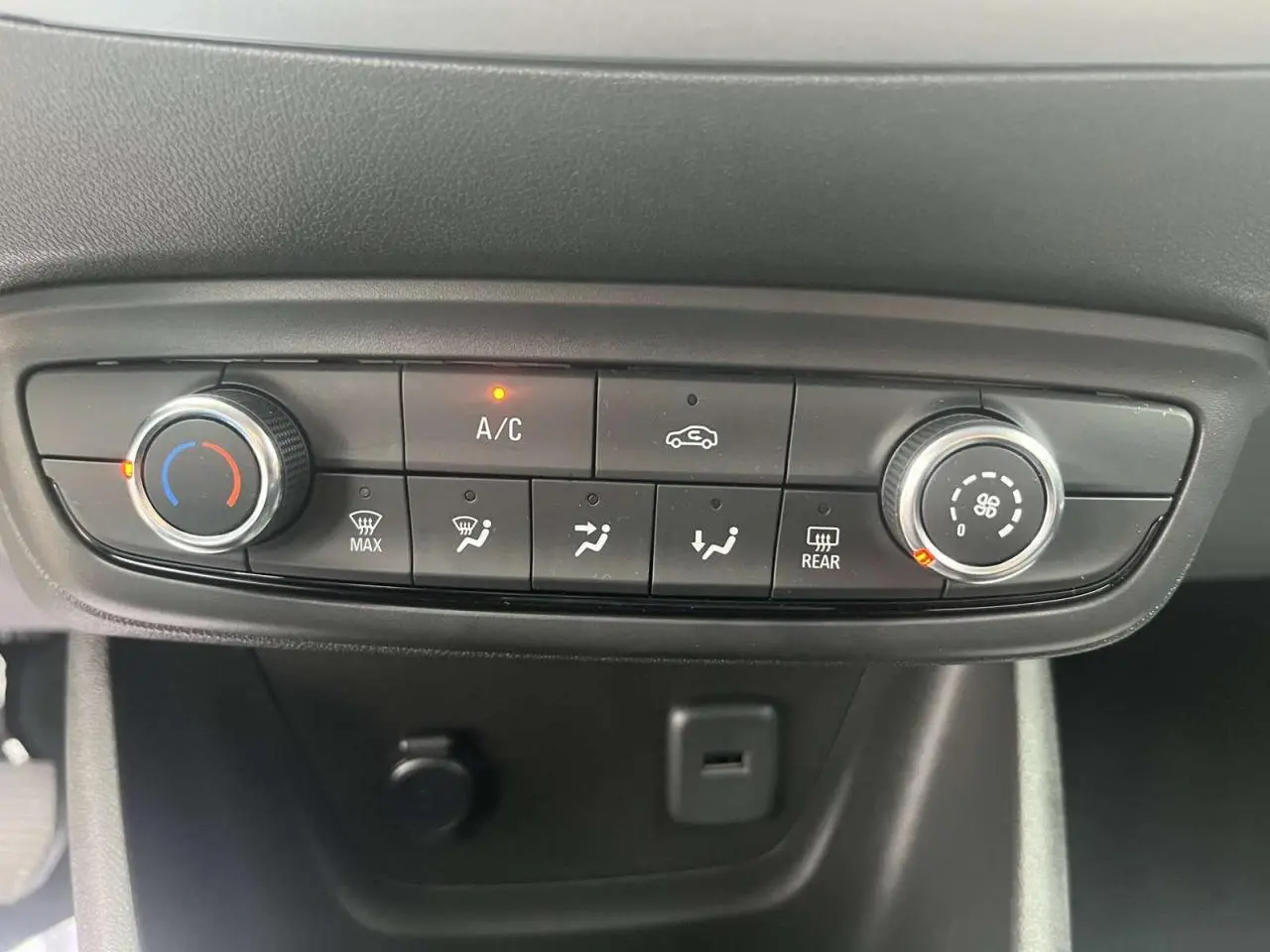 Vue rapprochée de la console de climatisation manuelle de l'Opel Crossland rouge, avec boutons et voyants allumés.