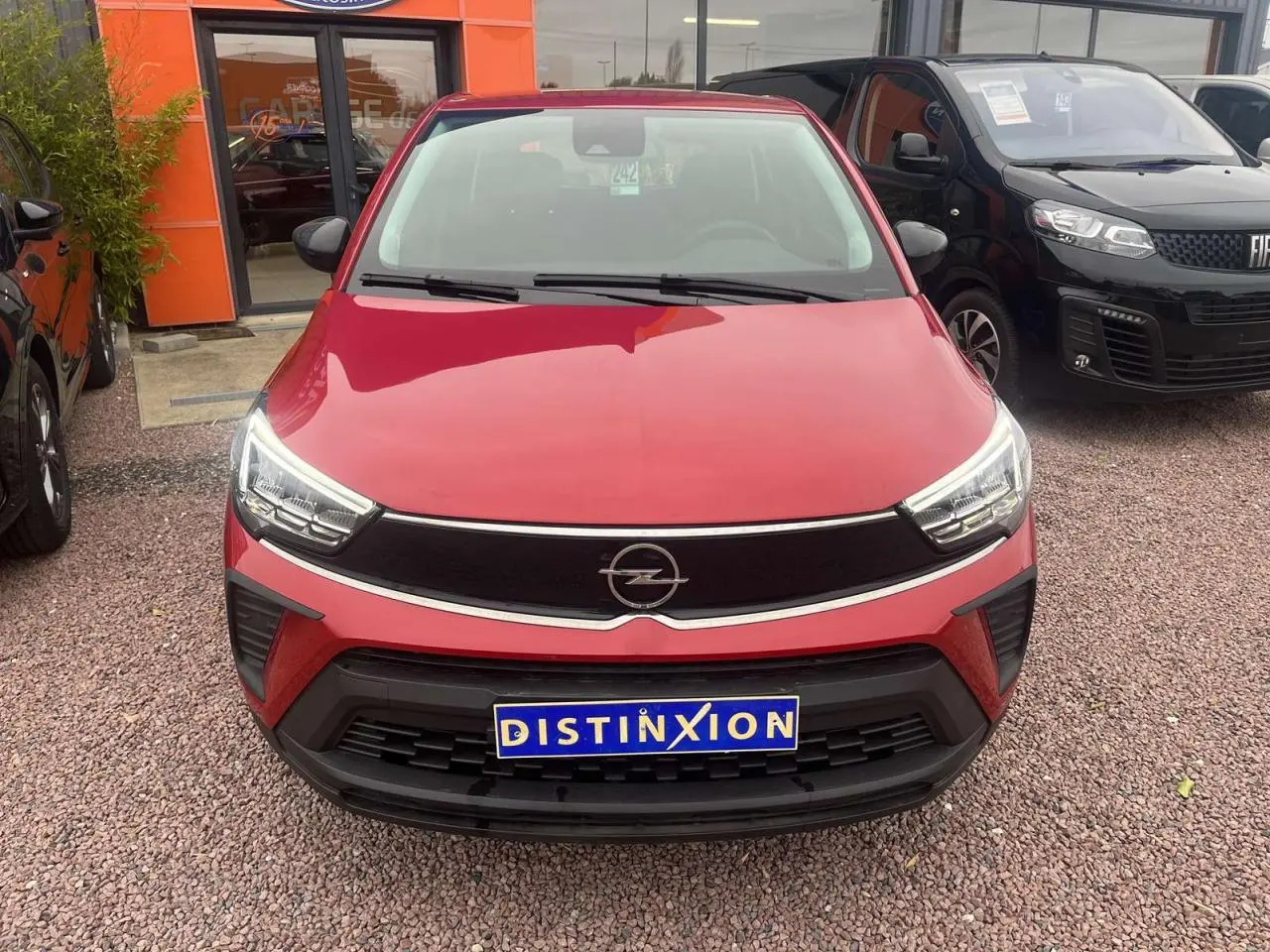 Vue frontale d'un Opel Crossland rouge métallisé 2022 avec calandre noire et phares LED distinctifs.