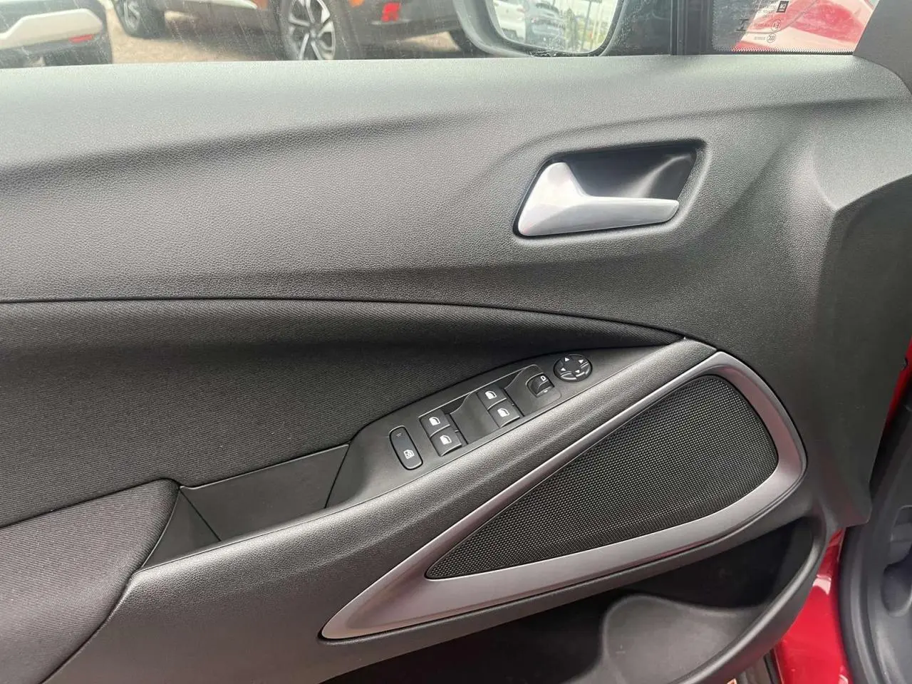 Intérieur côté gauche de la porte avant rouge d'une Opel Crossland 2022, avec commandes de vitres et poignée argentée.