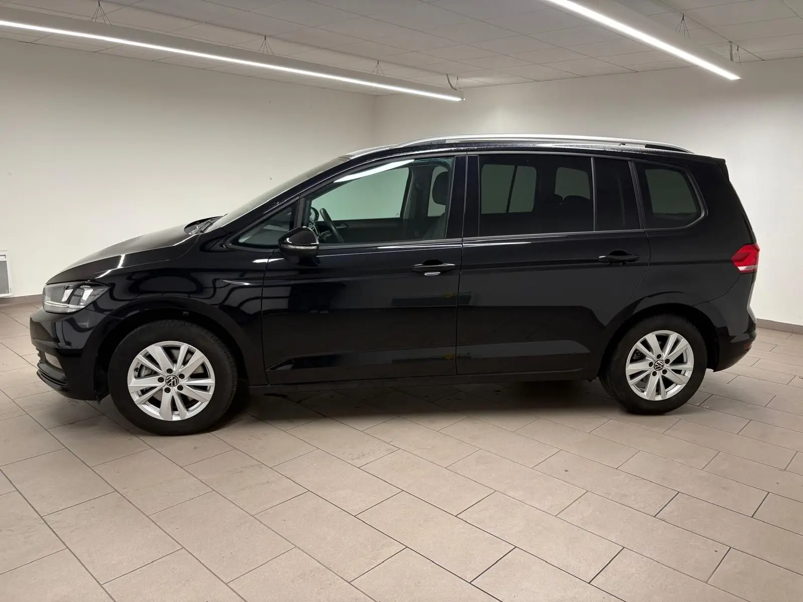 Profil côté gauche du Volkswagen Touran noir intense nacré 2024, monospace compact aux lignes épurées en intérieur neutre.