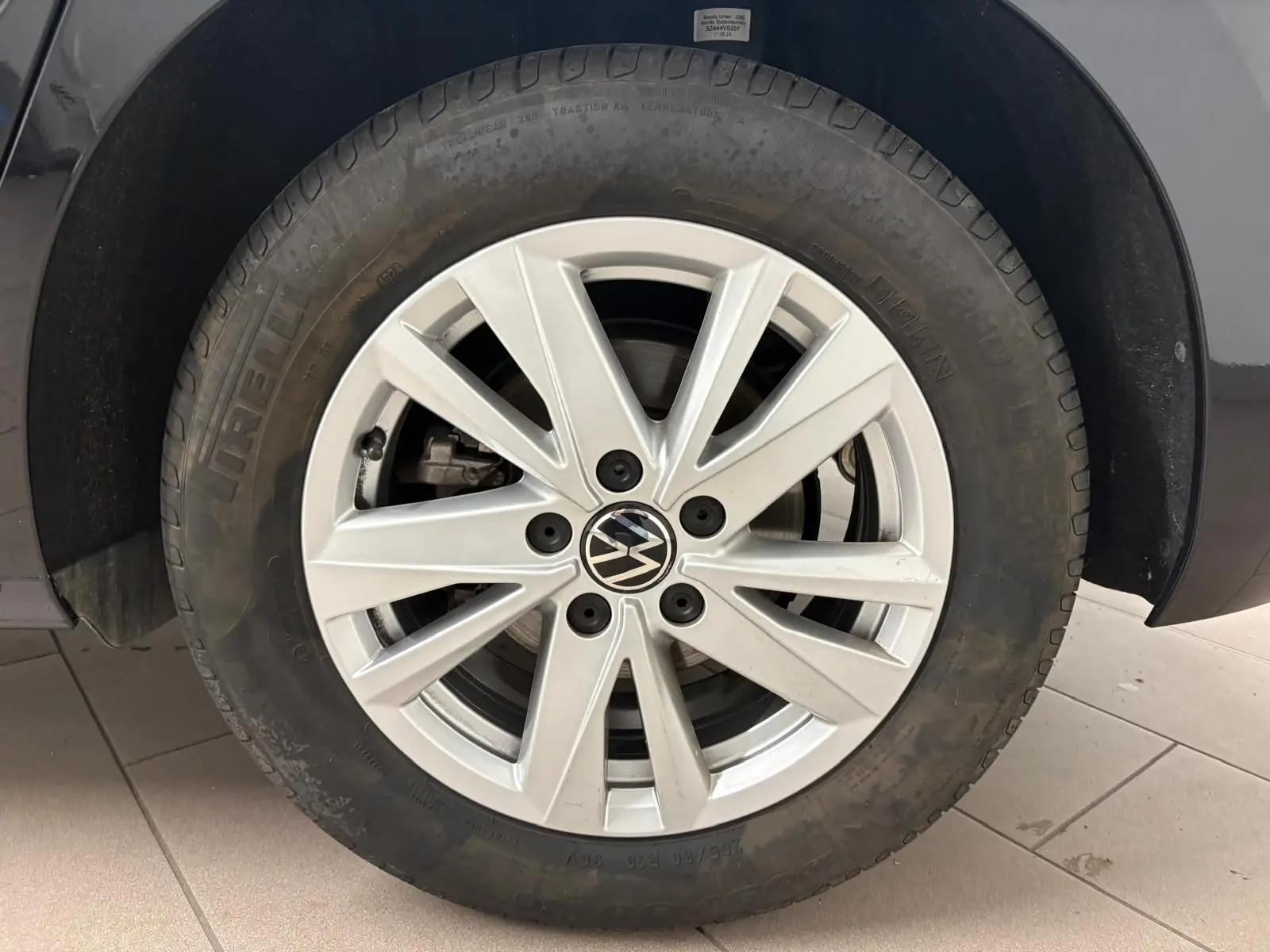 Gros plan sur la roue avant gauche du Volkswagen Touran 2024 noir intense nacré avec jante alliage à 10 branches.