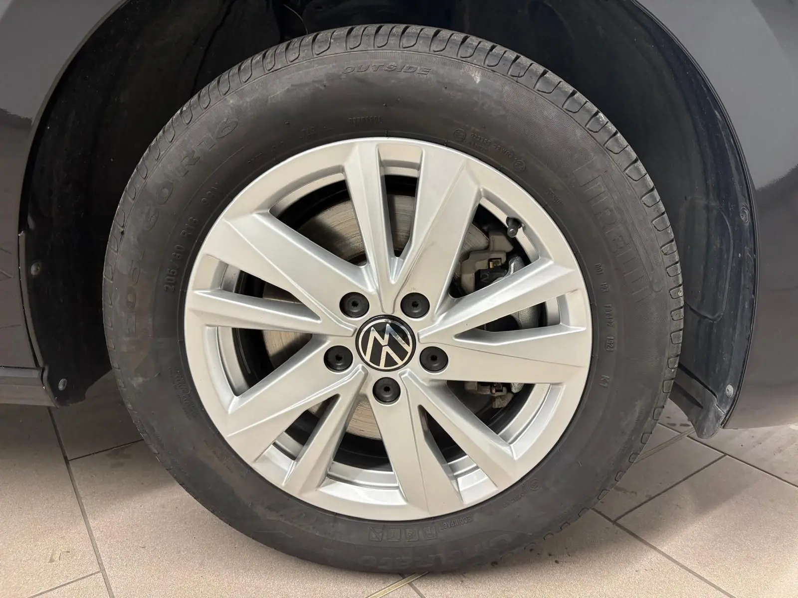 Gros plan sur la roue avant droite d'un Volkswagen Touran noir intense nacré avec jante alliage argentée.