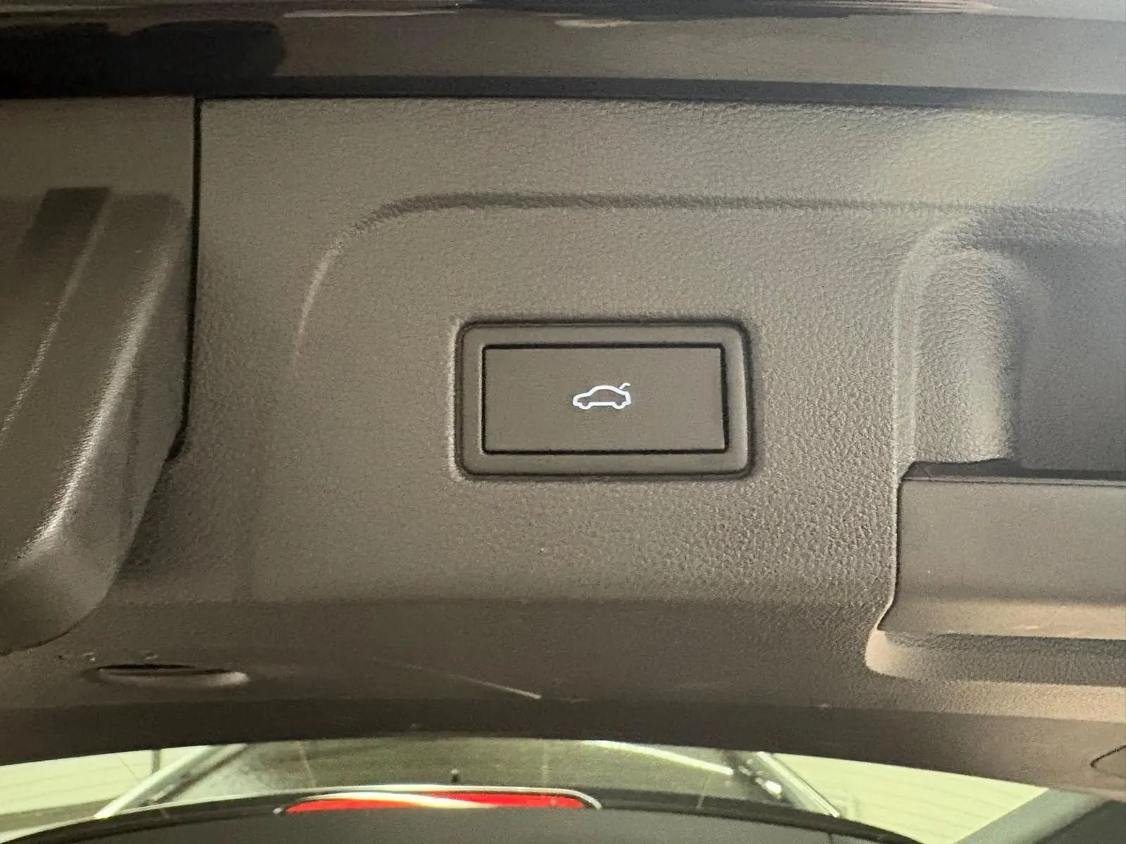Bouton d'ouverture électrique du hayon sur le panneau intérieur du coffre du Volkswagen Touran noir intense nacré.
