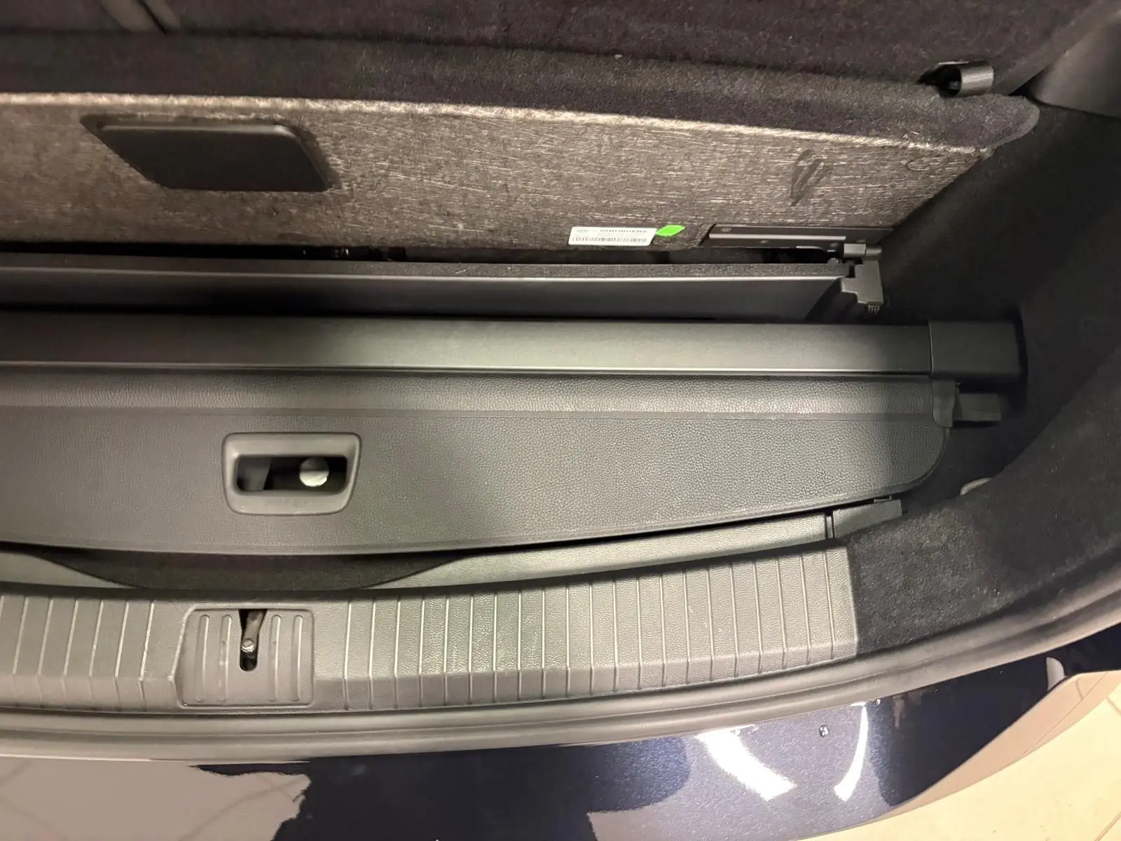 Gros plan sur le coffre ouvert du Volkswagen Touran noir intense nacré, montrant la plage arrière rétractable.