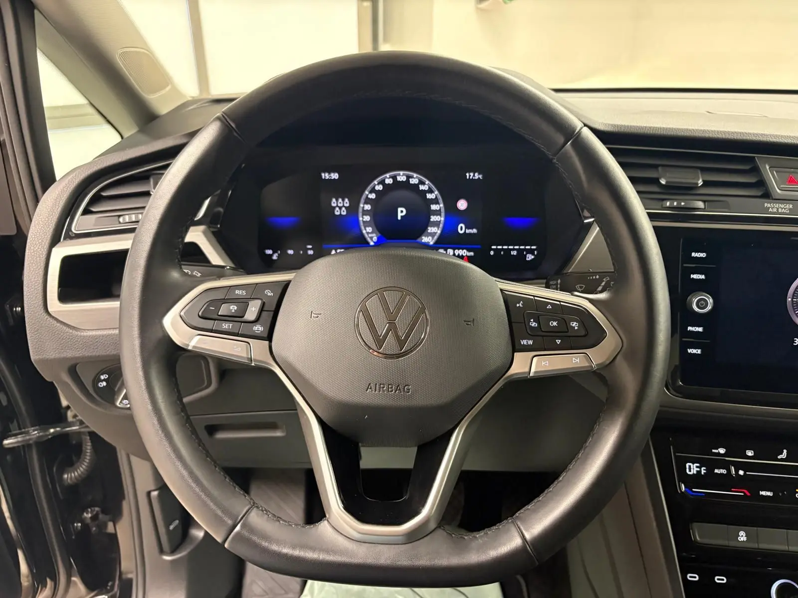 Vue rapprochée du volant cuir noir et du tableau de bord numérique du Volkswagen Touran 2024 Noir Intense nacré.