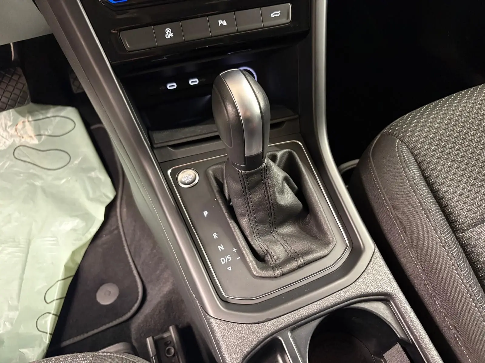 Gros plan sur la console centrale du Volkswagen Touran 2024 avec levier de vitesse automatique et bouton start/stop.