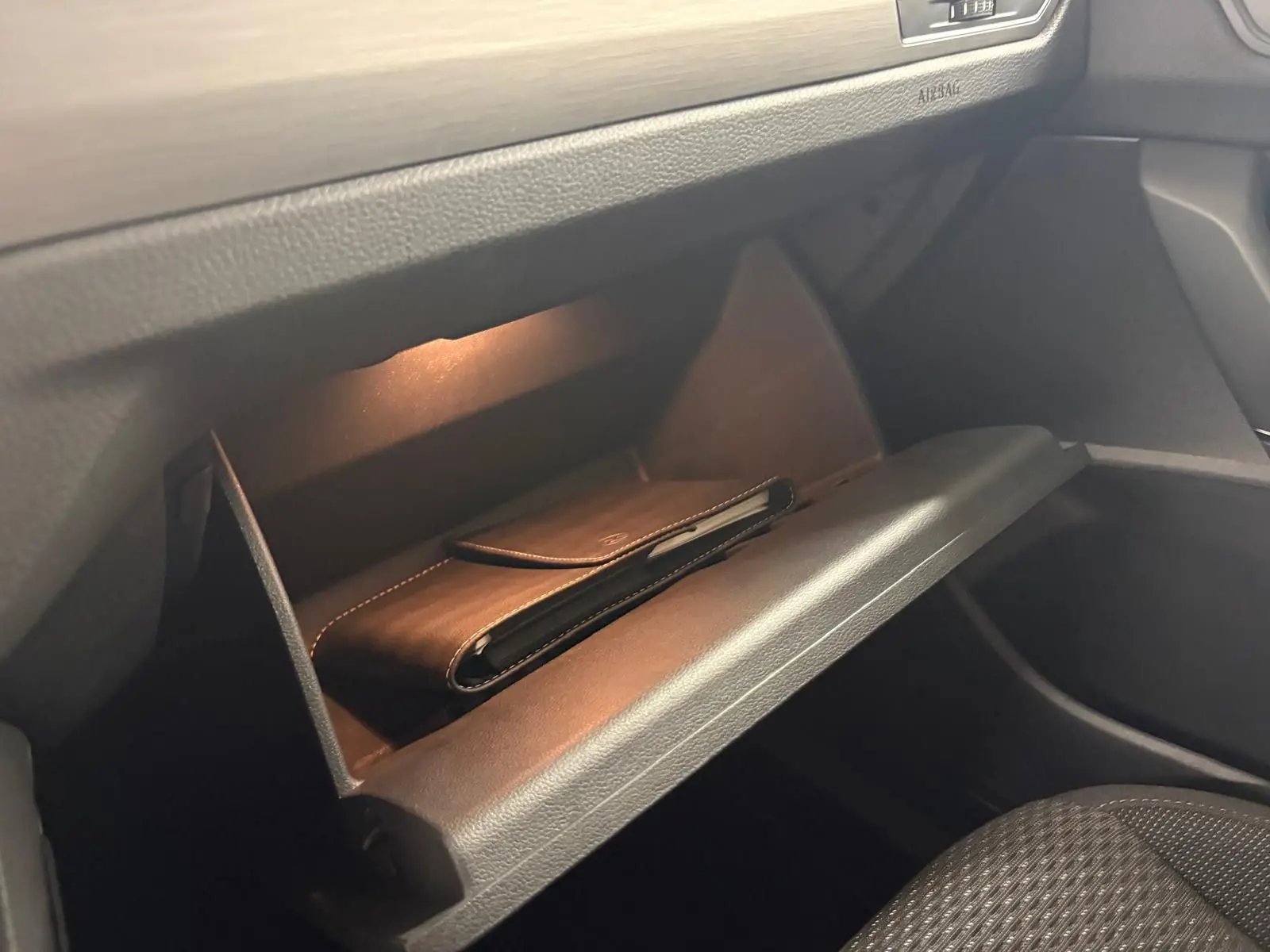 Gant de poche en cuir noir dans la boîte à gants éclairée côté passager du Volkswagen Touran 2024.