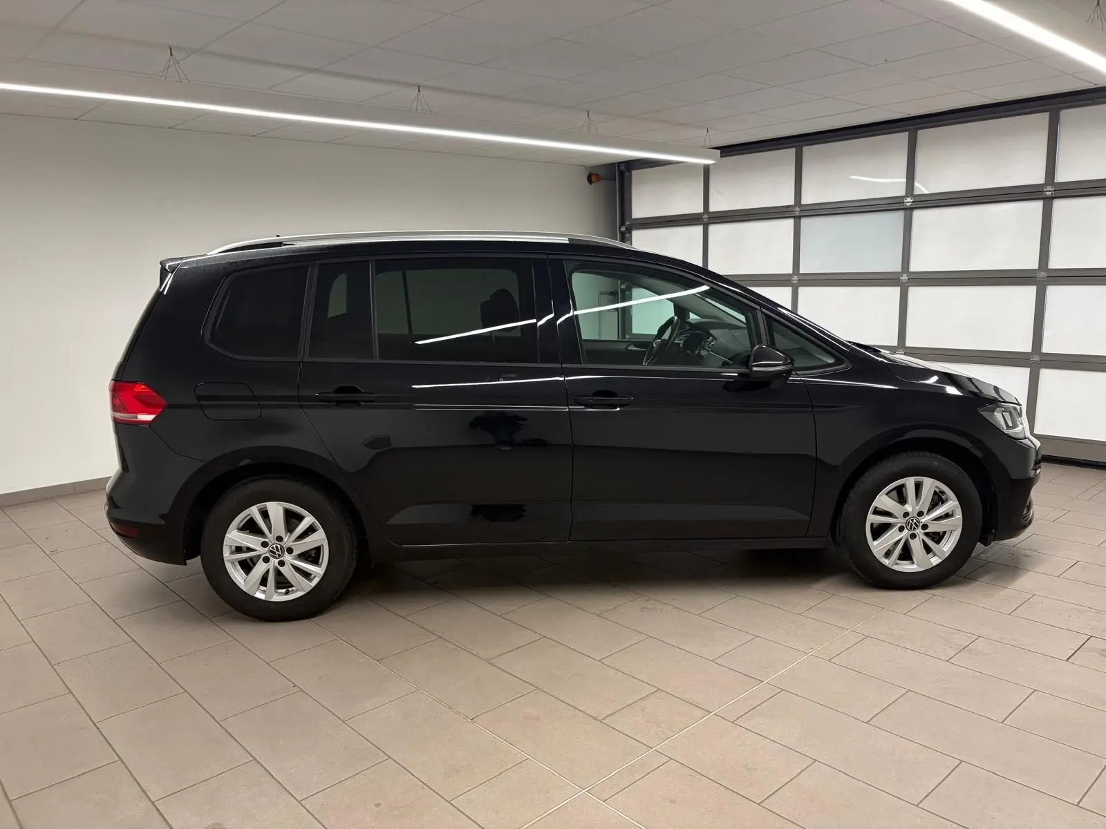 Profil droit d'un Volkswagen Touran noir intense nacré 2024, montrant ses lignes épurées et ses jantes alliage.