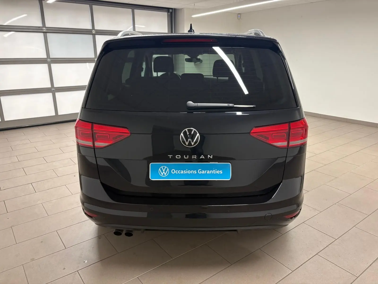 Vue arrière d'un Volkswagen Touran 2024 noir intense nacré, avec hayon électrique et badge Touran bien visible.
