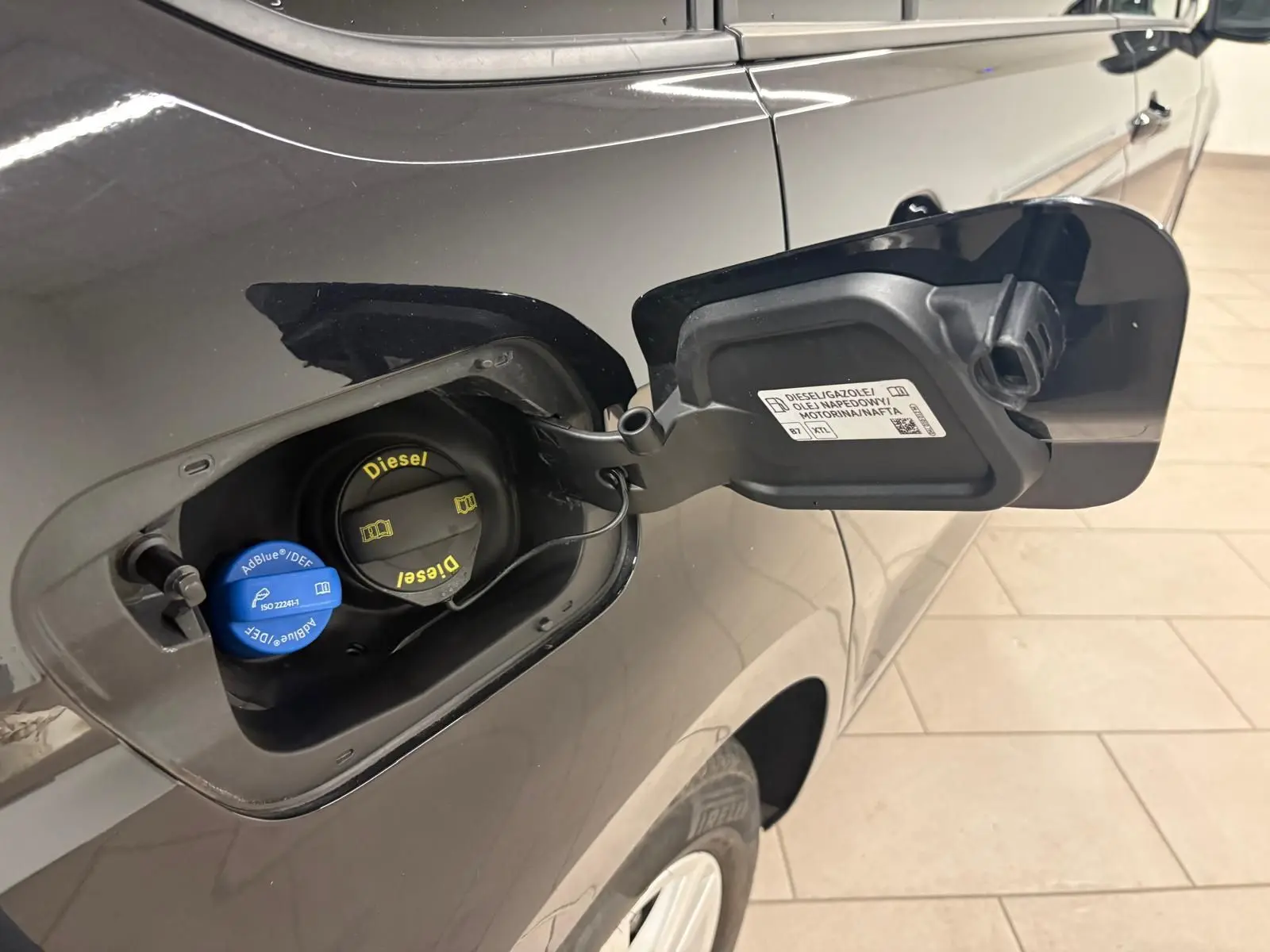 Bouchon de réservoir diesel ouvert côté gauche d'un Volkswagen Touran noir intense nacré 2024, détail carburant et AdBlue visible.
