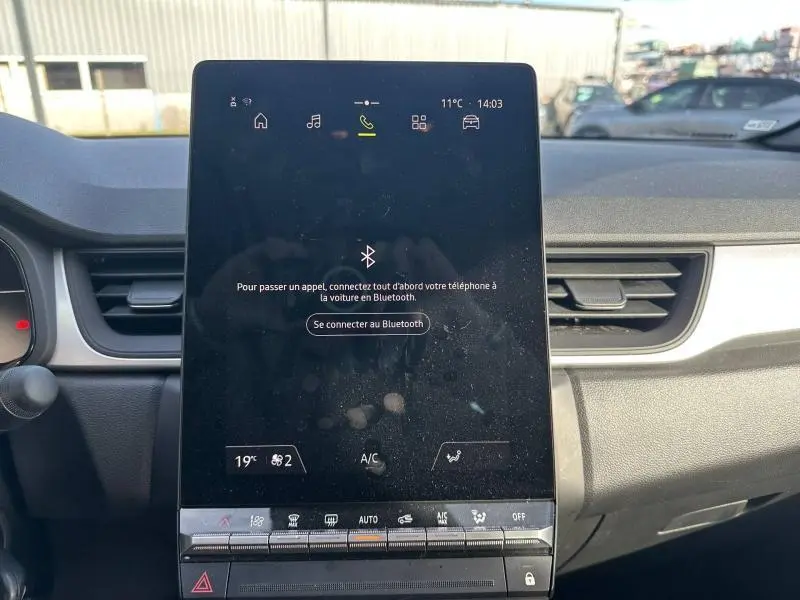 Vue intérieure centrée sur l'écran tactile du tableau de bord du Renault Captur blanc nacré/noir étoile 2025.