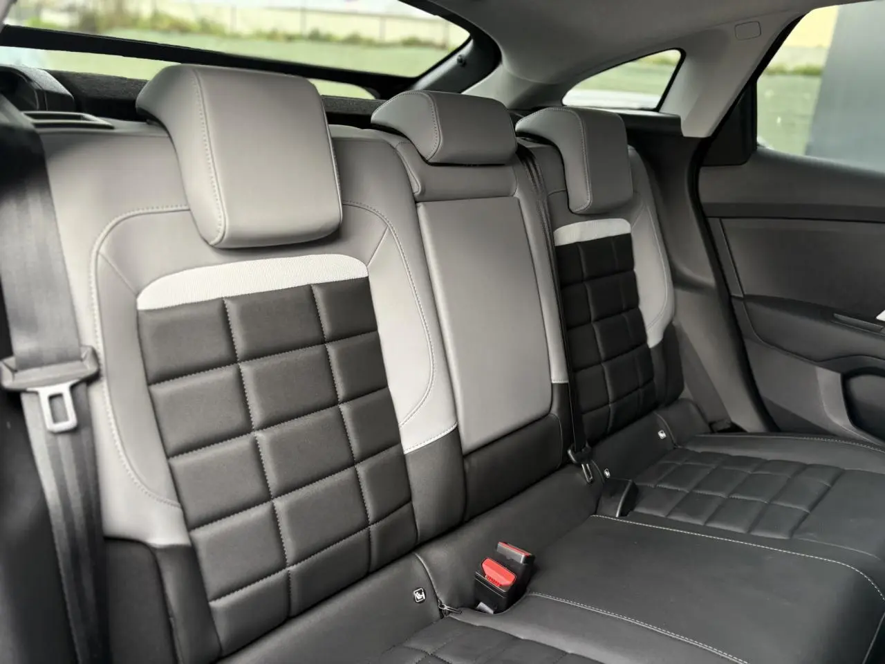 Vue intérieure arrière de la banquette bicolore noire et gris clair de la Citroën C4 Hybrid 2025 avec appuie-têtes intégrés.