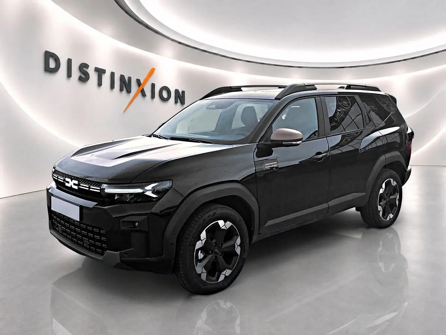 SUV Dacia Bigster noir en 3/4 avant droit, avec jantes alu et barres de toit visibles en showroom lumineux.