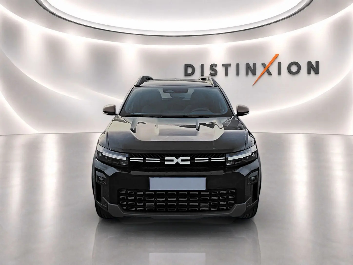 Vue avant d'un Dacia Bigster noir 2025 avec calandre marquée et barres de toit visibles en showroom lumineux.