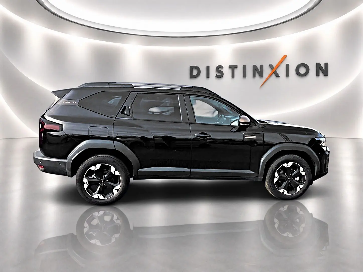 Profil droit du Dacia Bigster noir 2025 avec jantes alu noires et barres de toit, dans un showroom épuré.
