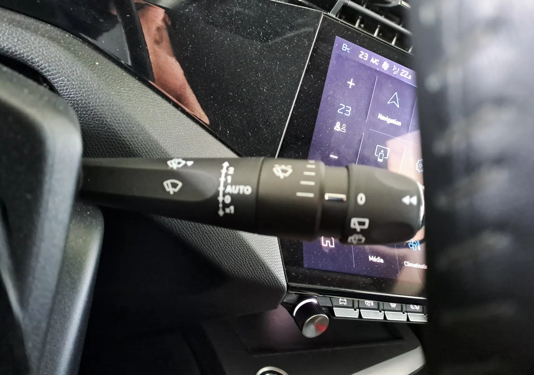 Gros plan sur la commande des essuie-glaces à gauche du volant dans l’habitacle noir du Peugeot 308 blanc Okenite 2024.