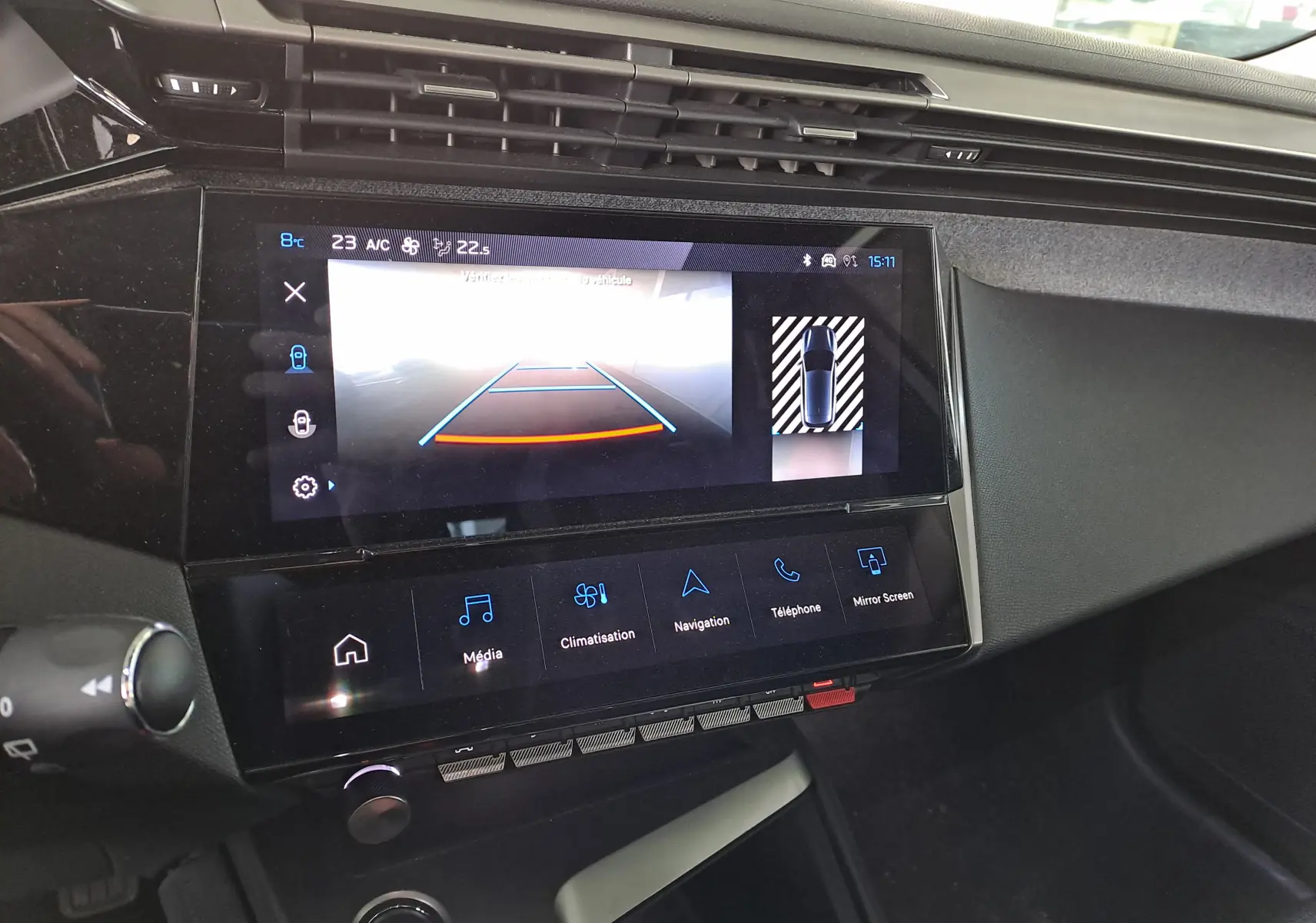 Écran tactile central de la Peugeot 308 2024 montrant la caméra de recul et les commandes multimédia sur tableau de bord noir.