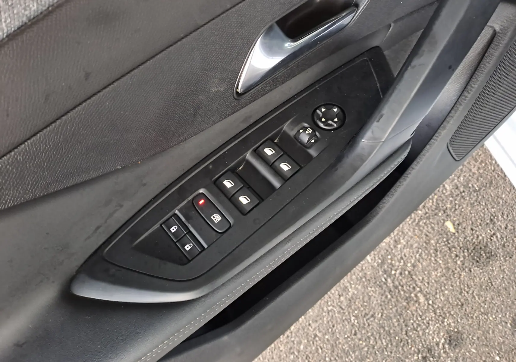 Panneau de commande des vitres et rétroviseurs côté gauche intérieur noir de la Peugeot 308 blanche 2024.