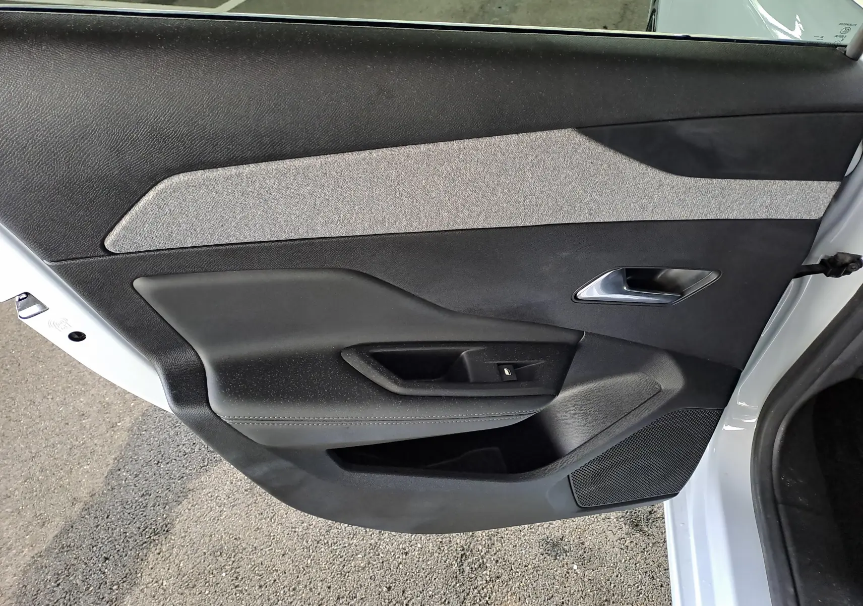 Porte côté gauche ouverte d'une Peugeot 308 blanche, intérieur noir avec bande grise texturée et poignée métal.