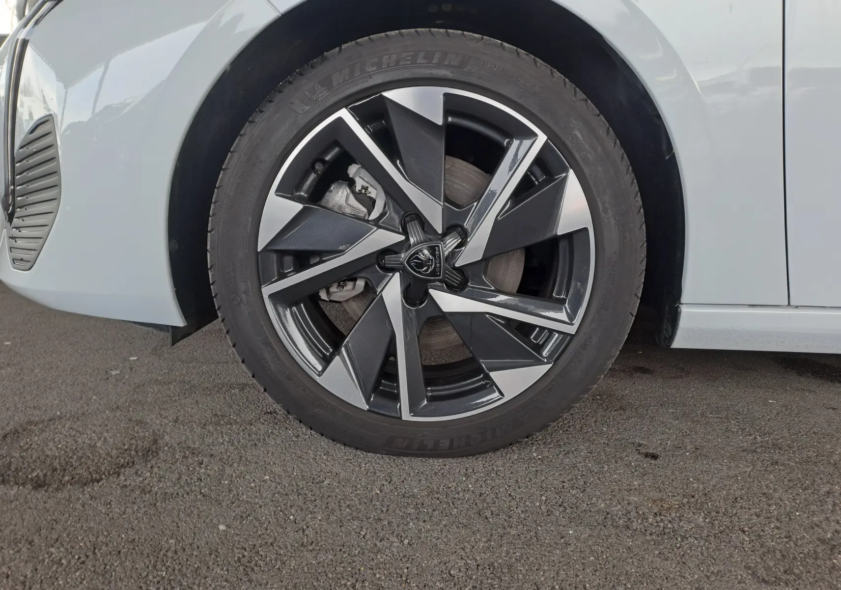 Gros plan sur la roue avant gauche de la Peugeot 308 blanche Okenite, mettant en valeur la jante alliage au design moderne.