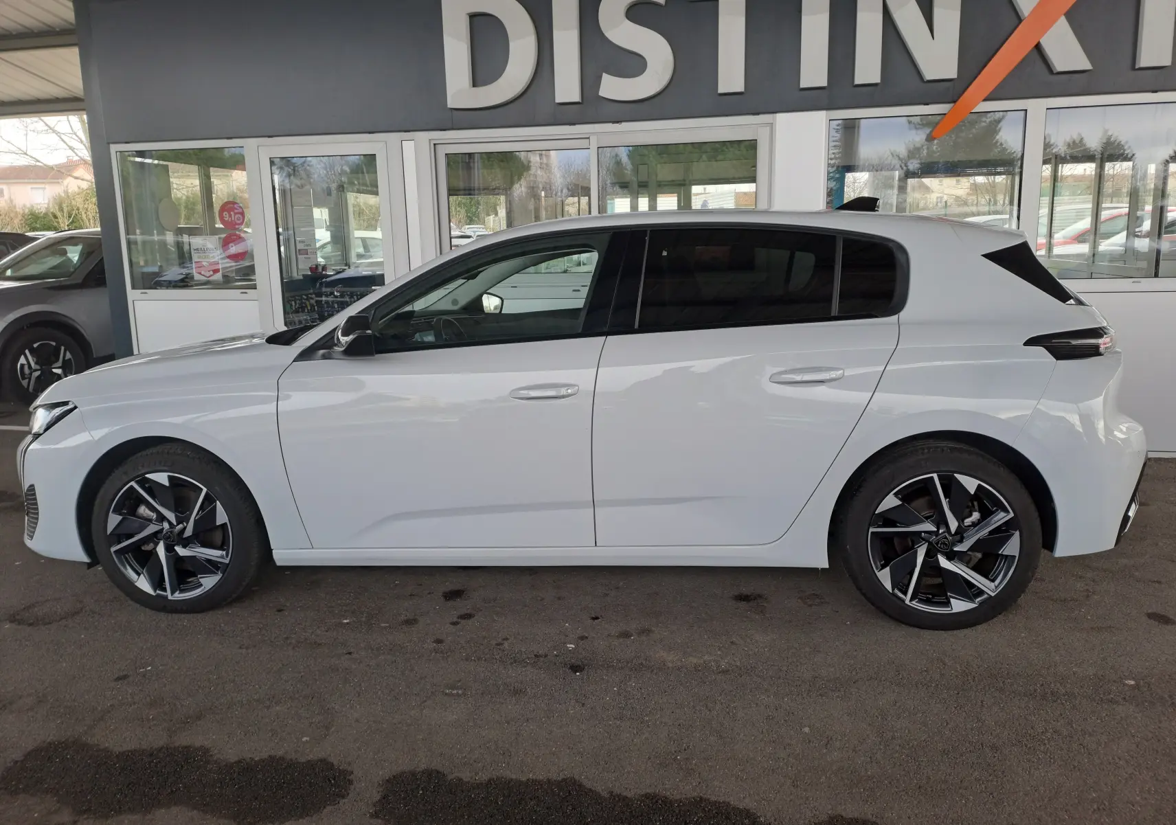 Profil côté gauche d'une Peugeot 308 blanche Okenite 2024 avec jantes alliage noires et vitres teintées.