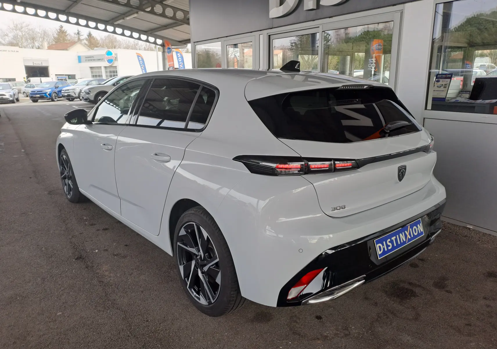 Peugeot 308 blanc Okenite vue 3/4 arrière droit, feux arrière LED et jantes alliage noires distinctives.