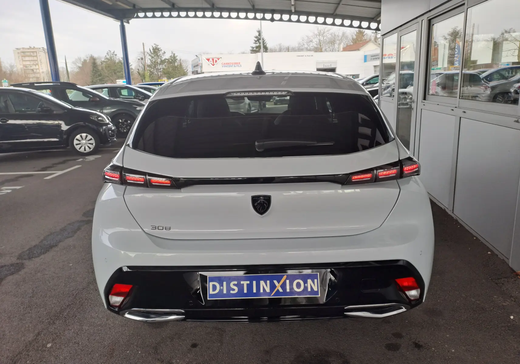 Vue arrière d'une Peugeot 308 blanche Okenite 2024 avec feux LED distinctifs et logo noir brillant.