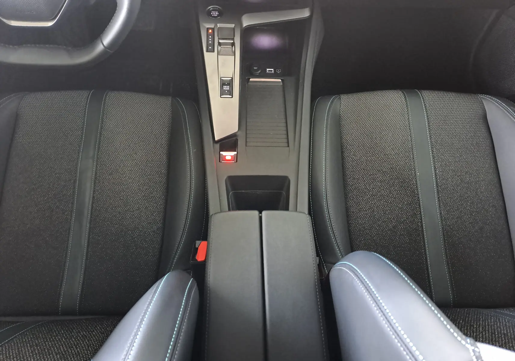 Vue intérieure centrée sur la console centrale et les sièges noirs du Peugeot 308 1.5 BlueHDi 130ch Allure 2024.