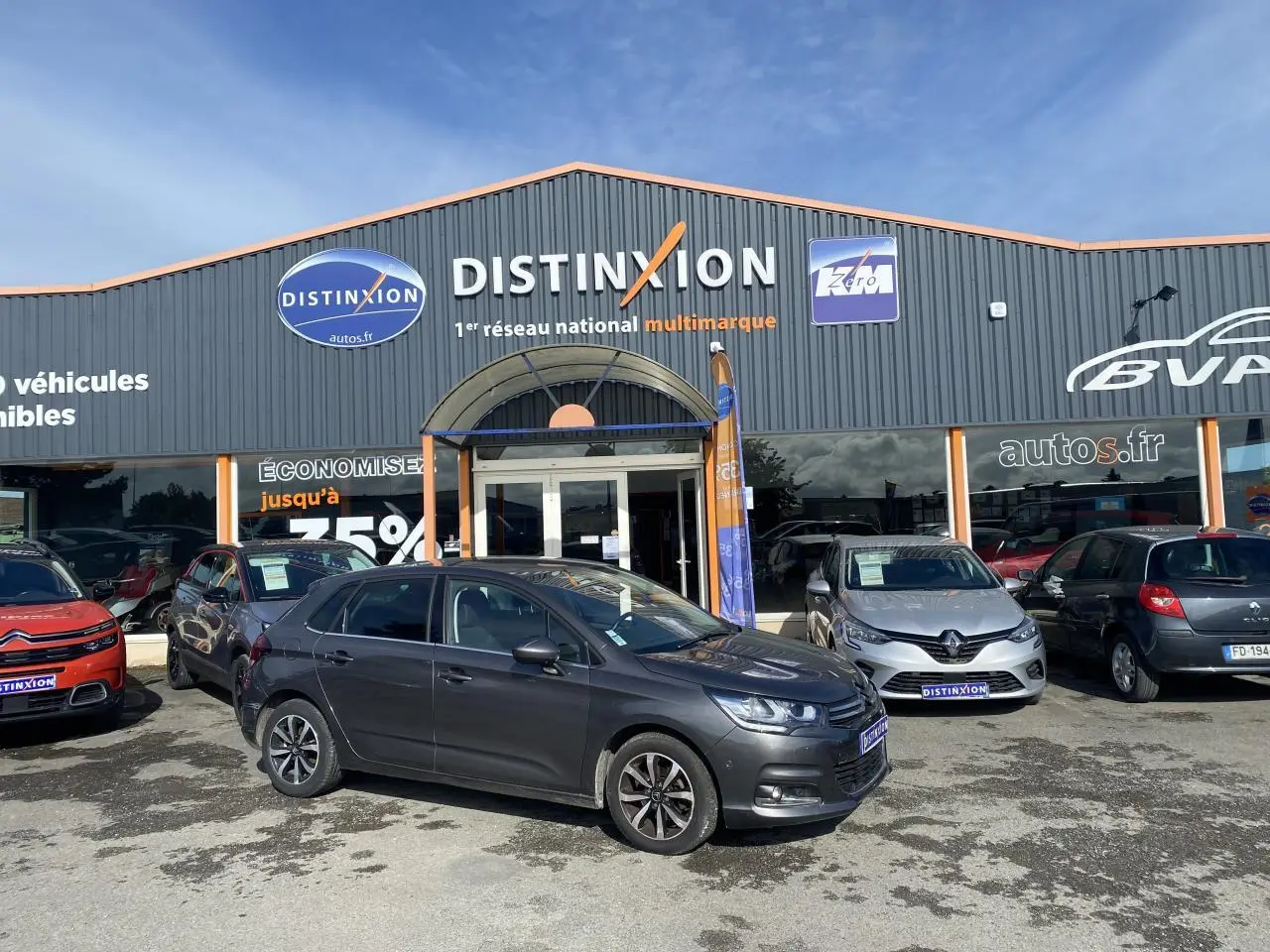 Citroën C4 gris platinium vue de profil côté gauche, stationnée devant un concessionnaire Distinxion.