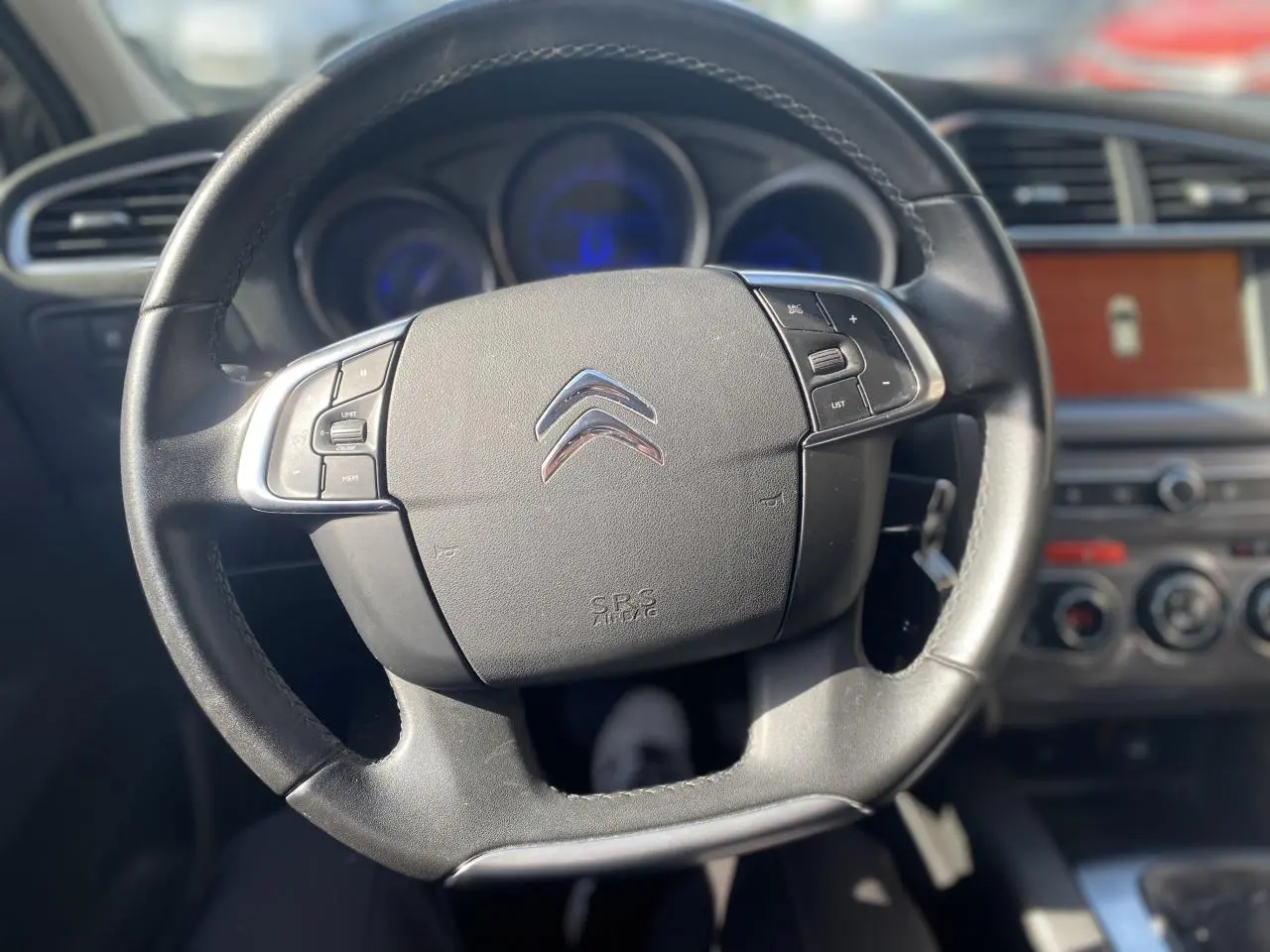 Volant en cuir noir de la Citroën C4 2017, avec commandes intégrées et tableau de bord flou en arrière-plan.