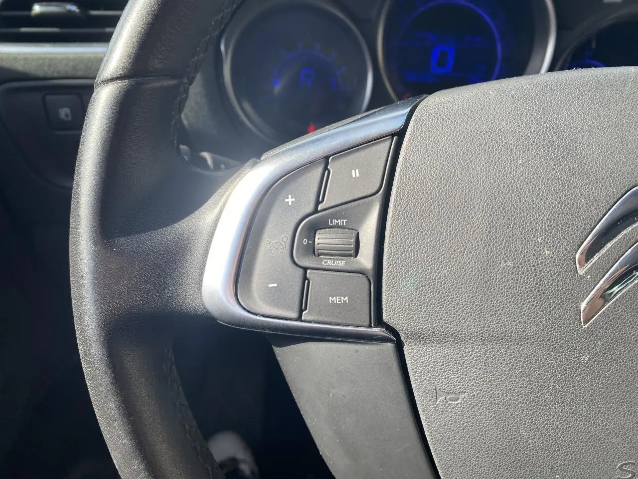 Gros plan sur le côté gauche du volant noir d'une Citroën C4 2017 avec commandes de régulateur de vitesse.