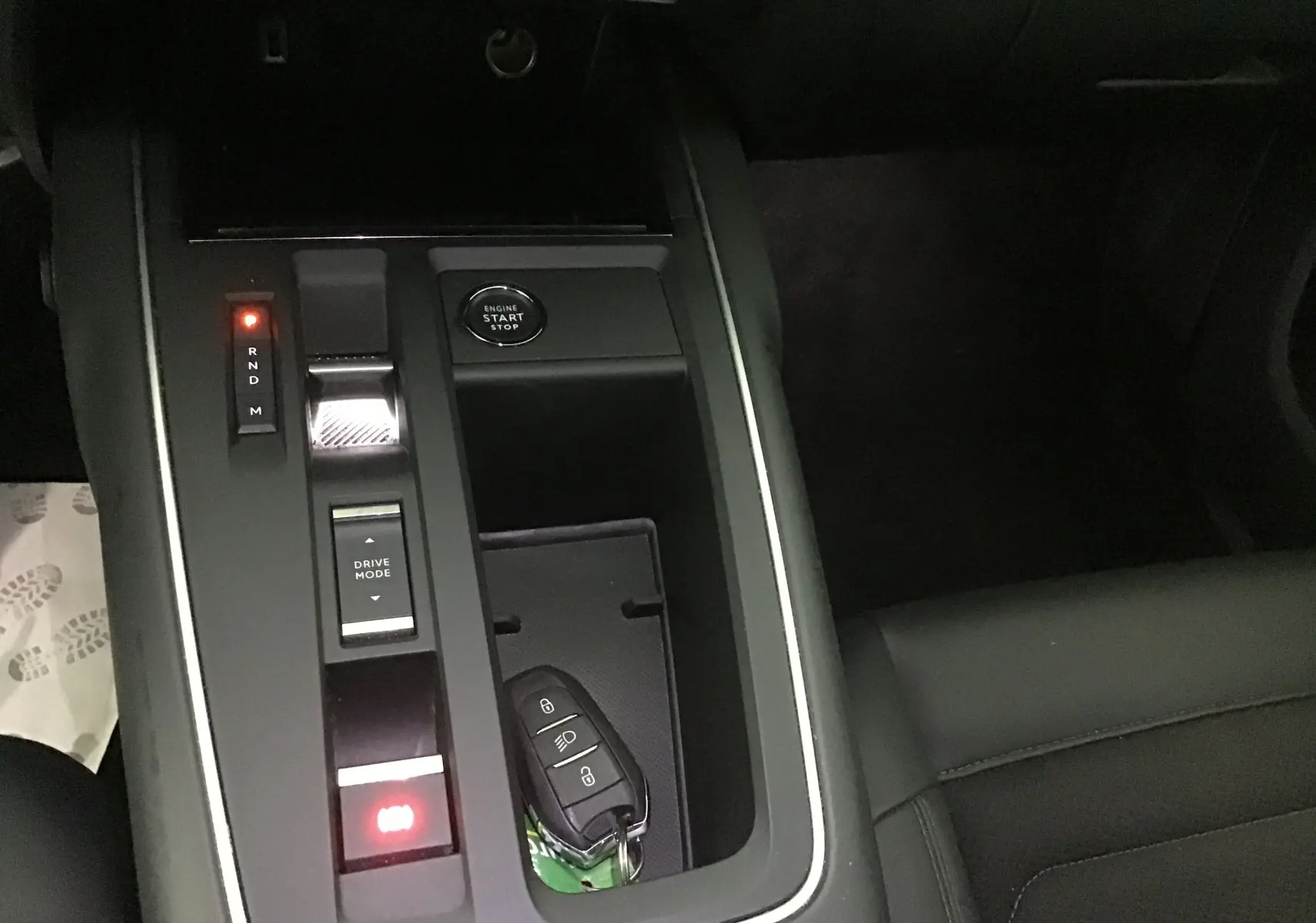 Vue rapprochée de la console centrale noire du Citroën C5 Aircross 2024 avec clé mains libres posée et boutons lumineux.