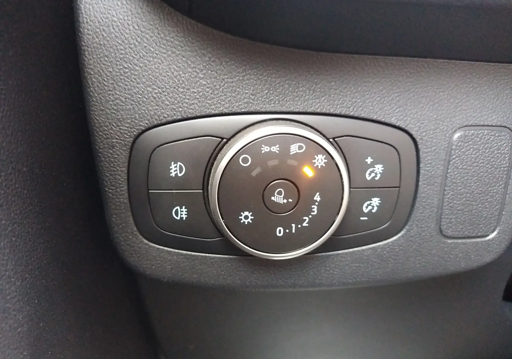 Gros plan sur la commande d'éclairage avec réglage de la luminosité dans l'habitacle d'une Ford Puma blanche.