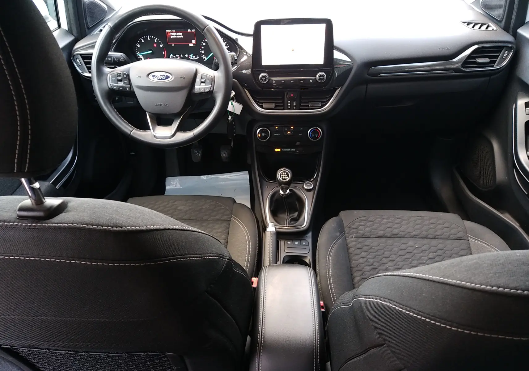 Vue intérieure avant du Ford Puma 1.0 EcoBoost hybride, volant multifonction et levier de vitesse manuel visibles.