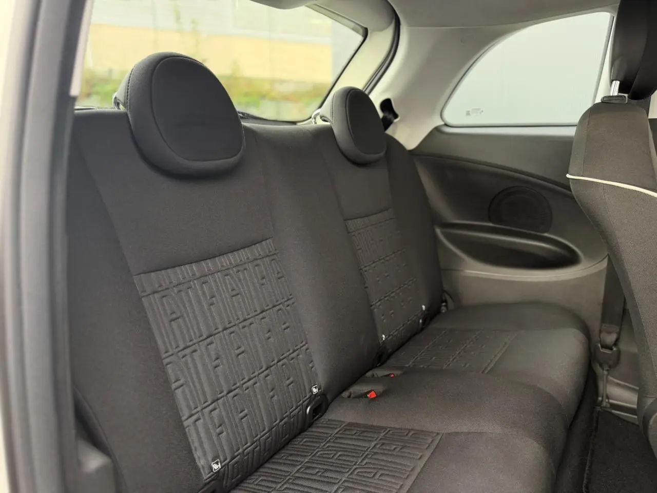 Vue rapprochée de la console centrale de la Fiat 500 électrique blanche, montrant les commandes de climatisation et ventilation.