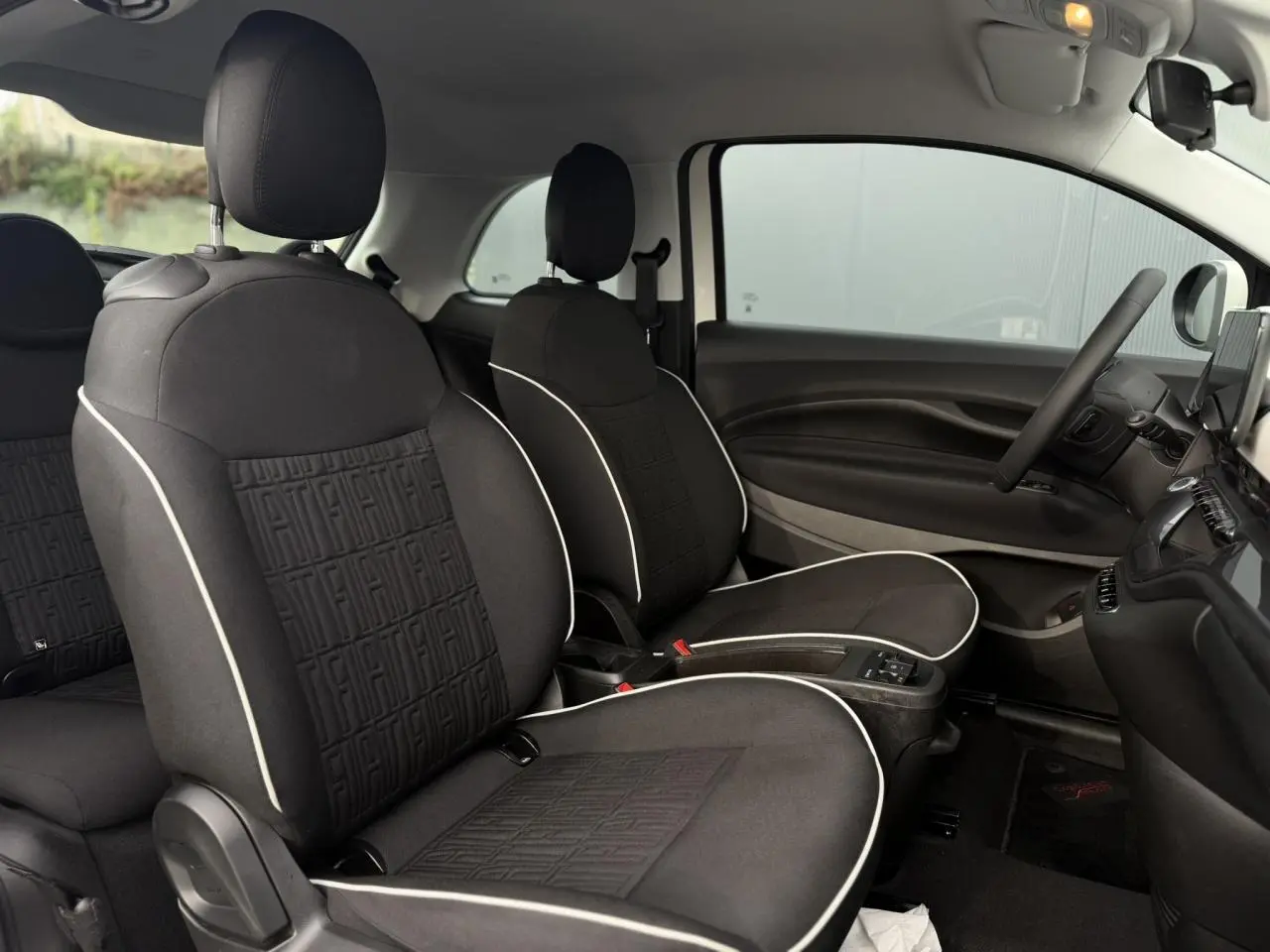 Gros plan sur l'avant droit blanc de la FIAT 500 électrique, mettant en valeur le phare rond et la jante alu stylisée.