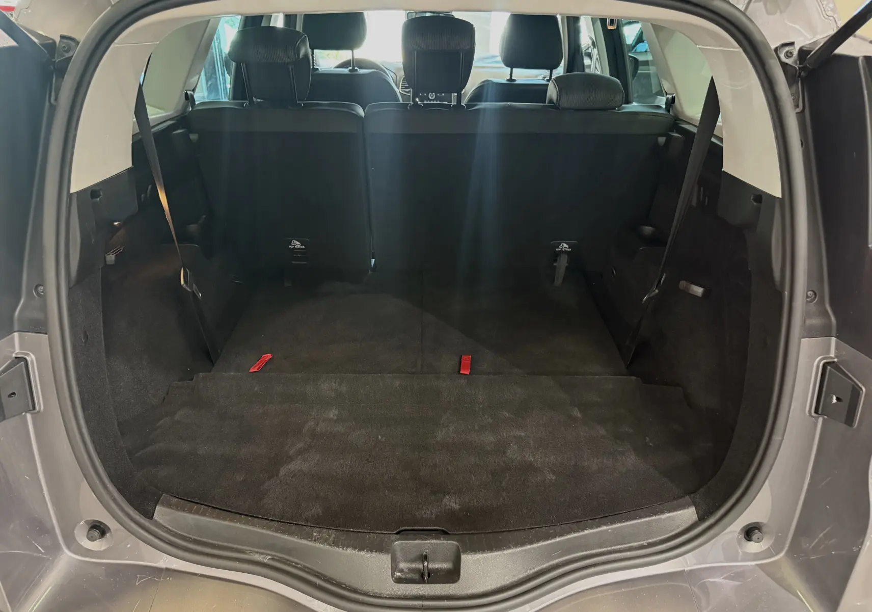 Coffre ouvert vu de l'arrière du Renault Grand Scenic IV Business gris Cassiopée, montrant l'espace de chargement et les sièges arrière.