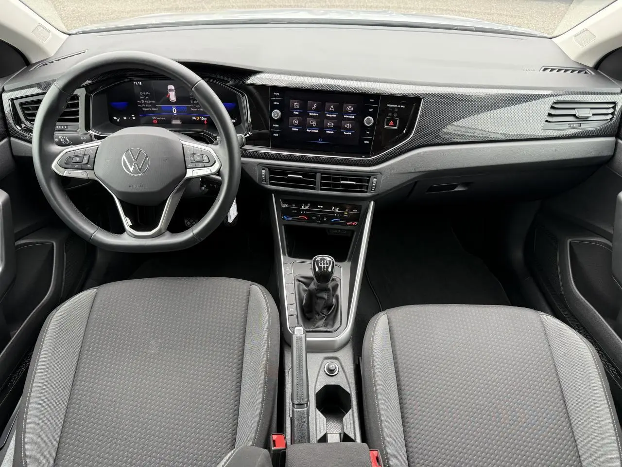 Vue intérieure frontale du tableau de bord et volant cuir multifonctions du Volkswagen Taigo gris reflet d'argent, avec boîte manuelle.