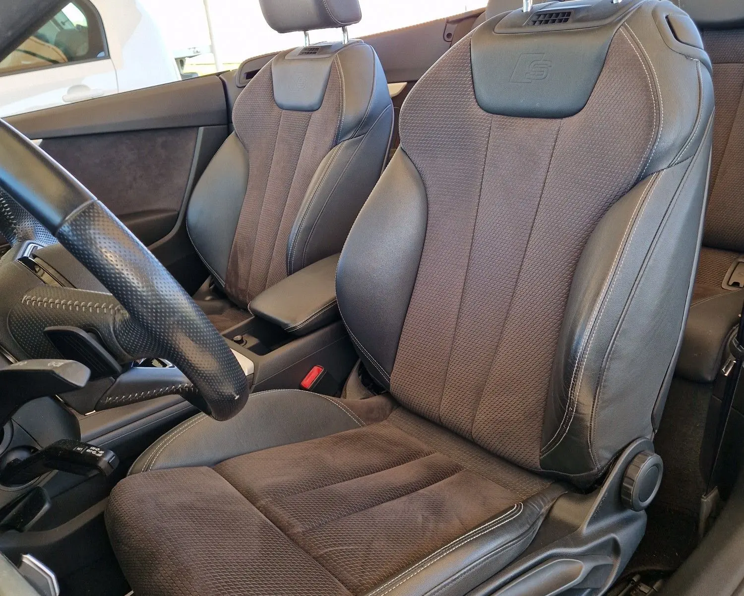 Gros plan sur les sièges avant en cuir noir de l'Audi A5 Cabriolet 2.0 TDI 190CH, avec logo S embossé sur les appuie-têtes.