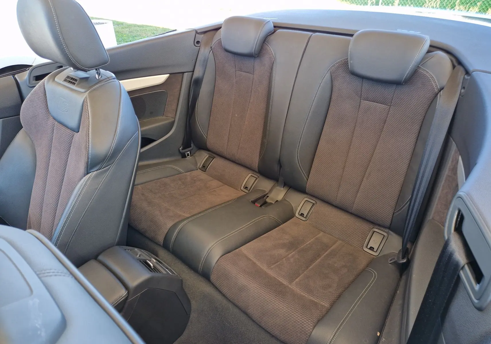 Vue intérieure arrière de l'Audi A5 Cabriolet 2017, sièges en cuir et tissu noir avec appuie-têtes intégrés.