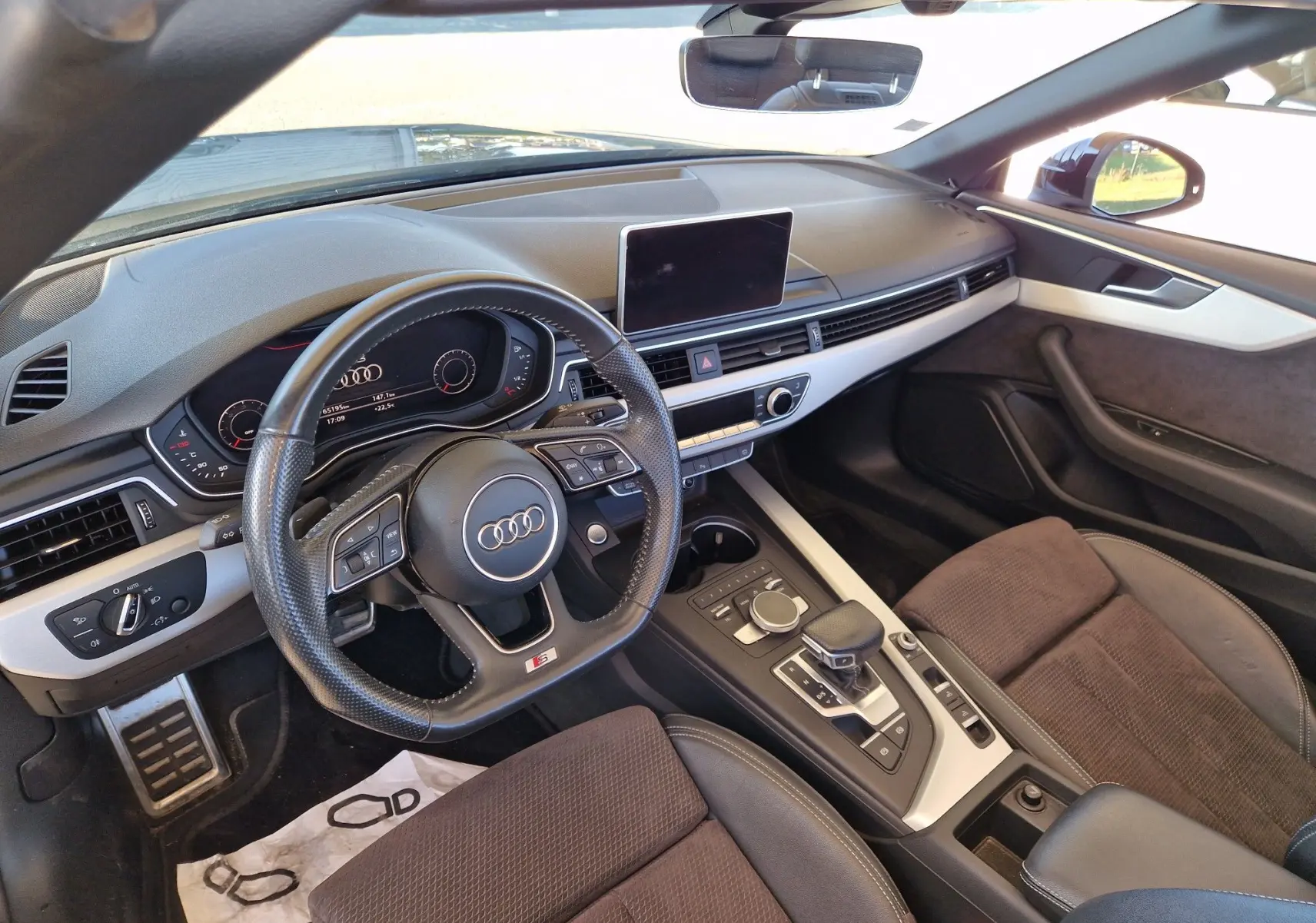 Intérieur de l'Audi A5 Cabriolet 2017 vu côté conducteur, tableau de bord noir avec volant cuir multifonction et écran central.