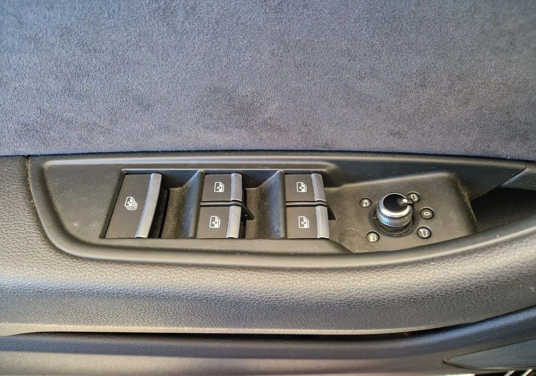 Gros plan sur les commandes de lève-vitres et réglage des rétroviseurs côté conducteur d'une Audi A5 Cabriolet noir 2017.